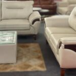 Luxury beige sofa set with wooden accents, paired with a glass-top center table for a stylish living room setup